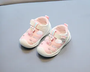 Close-up of pink and white baby sandals with cute bear decoration and closed toe design