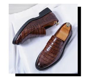 Close-up detail of brown crocodile embossed leather loafers featuring durable black soles