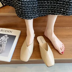 Dettaglio di eleganti sabot beige a punta su sfondo in legno con una rivista patinata