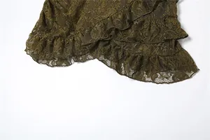 Gros plan sur la texture de dentelle vert foncé et l'ourlet à volants de la jupe.