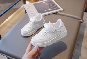 Detailed view of white breathable mesh children sneakers with velcro closure strap