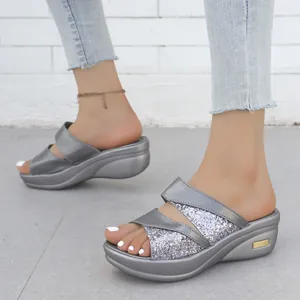 Primo piano dettagliato di eleganti sandali con zeppa e glitter argento per donna.