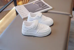 Detailed view of children's white sneakers with Velcro straps and breathable holes