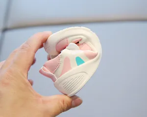 Detail showing the flexible soft sole of toddler walking shoes in pink and white.