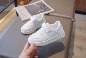 Close-up of kids' white sneakers with Velcro strap and breathable perforated toe design