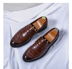 Detail shot of brown men's loafers featuring crocodile pattern on white silk background