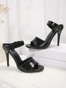 Macro detail of black crocodile embossed high heel stiletto mule sandals with open toe
