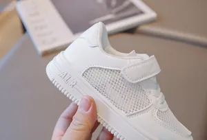 Close-up of white children's mesh sneakers with breathable side panels and velcro strap.