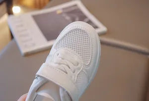 Close-up detail of white breathable mesh and Velcro strap on children's sneakers