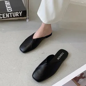 Dettaglio dell'elegante trama a pieghe incrociate dei sabot in pelle nera a punta.