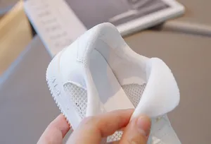 Detailed macro view showing the breathable mesh and padded heel of white children sneakers