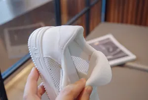 Macro view of breathable white mesh children's sneakers showing soft heel detail