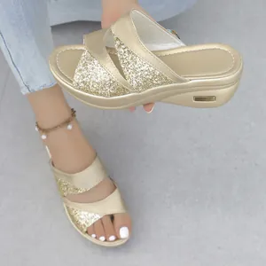 Vista dettagliata dei sandali con zeppa glitterati dorati con design a fasce incrociate