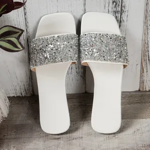 Top view of white flat sandals with sparkling silver sequin straps for summer