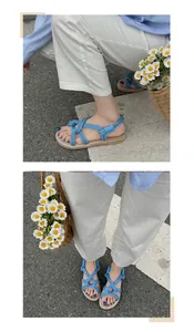 Detail von sommerlichen Sandalen aus blauem Seil mit gewebten Strohsohlen auf der Straße