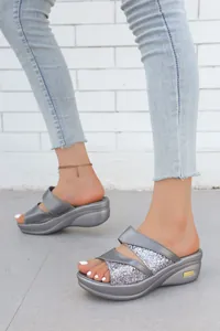 Vista dettagliata di eleganti sandali con zeppa glitterati argento con jeans