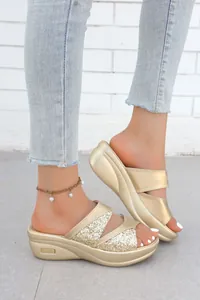 Dettaglio ravvicinato dei sandali con zeppa dorati e glitterati con suola platform