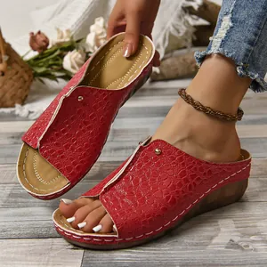 Detailopname van rode sleehak sandalen met krokodillenprint en witte stiksels
