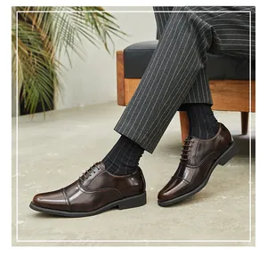 Men's brown leather cap-toe Oxford shoes styled with grey striped suit pants