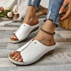 Close-up van witte sleehaksandalen met krokodillenpatroon en open teen gedragen.