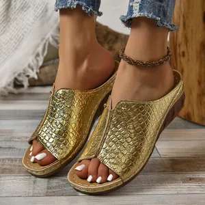 Close-up detail van gouden platform muiltjes met krokodillenprint en peep-toe model