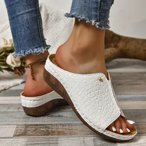 Detail van witte platform slippers met krokodillenprint en open teen.