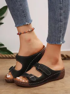Detailaufnahme der stilvollen schwarzen Keilsandalen mit Schnallenriemen und Nähten