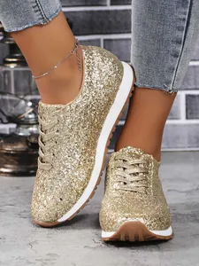 Gros plan de baskets dorées à paillettes pour femmes avec semelle blanche et lacets