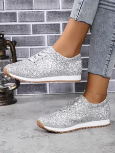 Détail de baskets pailletées argentées pour femmes avec semelles compensées et lacets