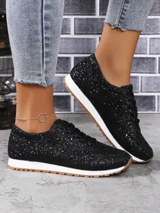 Gros plan de baskets à lacets noires pailletées portées avec un jean en denim court