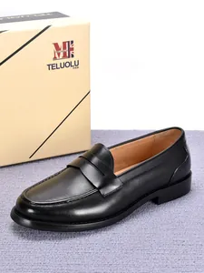 Detailweergave van zwarte lederen herenloafers naast merk schoenendoos.