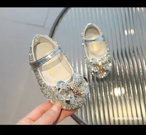 Détail de chaussures argentées pailletées pour filles avec un nœud en strass chic.