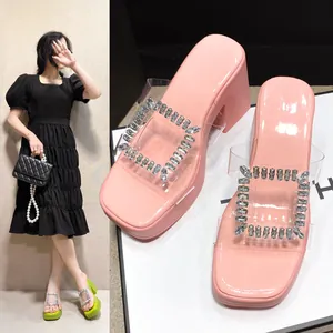 Detailed view of pink platform slides featuring a transparent strap and rhinestone buckle