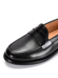 Close-up detail van zwarte leren penny loafer met hoogwaardige stiksels en textuur
