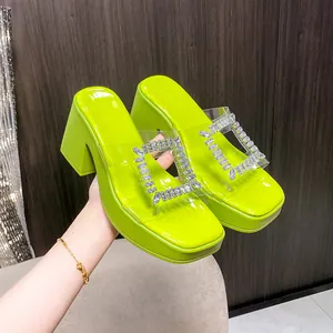 Detail of lime green platform mules featuring a clear strap and sparkling rhinestone buckle.