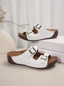 Seitenansicht weißer Plateausandalen mit doppelten Schnallenriemen im minimalistischen Studio