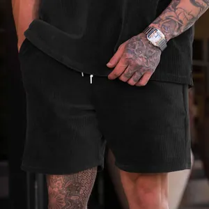 Vista dettagliata dei pantaloncini in velluto a coste neri da uomo con coulisse bianca.