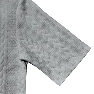 Nahaufnahme der Zopfmuster-Jacquard-Textur auf dem kurzärmeligen Herrenhemd in Grau.