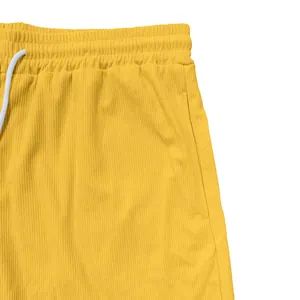 Dettaglio di pantaloncini sportivi in velluto giallo con coulisse e tasche laterali