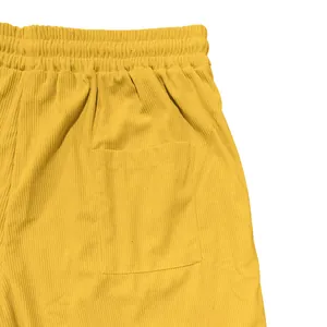 Close-up van gele corduroy shorts met elastische tailleband en zijzak detail.