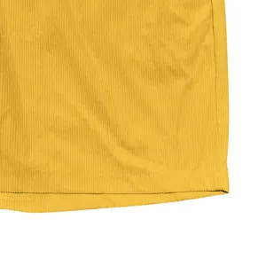 Primo piano del tessuto di velluto a coste giallo con trama a costine e bordo cucito.
