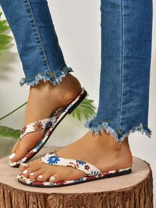 Close-up of women's flat flip-flops with colorful floral print for summer beach wear