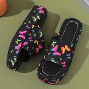 Detail view of stylish platform slides featuring colorful butterfly prints on black straps.