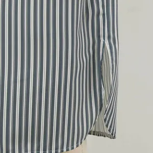 Détail d'une robe rayée bleue et blanche montrant la fente latérale et l'ourlet.