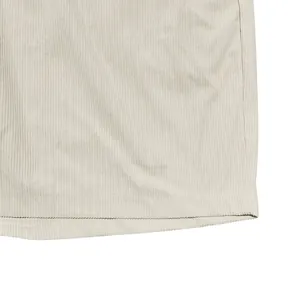 Dettaglio dei pantaloncini in velluto a coste beige con trama fine e orlo curato