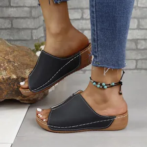 Detailed view of women's black wedge slides featuring white stitching and peep-toe