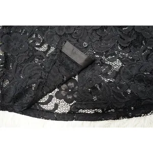 Primer plano detallado de tela de encaje floral negro con delicado cierre de botón.