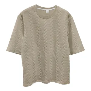 Nahaufnahme des beigen Zopfstrick-Jacquard-Stoffes auf einem lässigen Herren-T-Shirt