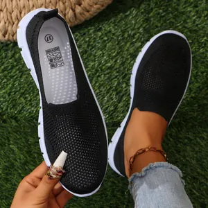 Dettaglio ravvicinato delle scarpe piatte in rete nera traspirante per donna su erba verde