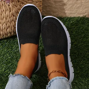 Vista dettagliata di scarpe slip-on in rete nera traspirante da donna su erba verde